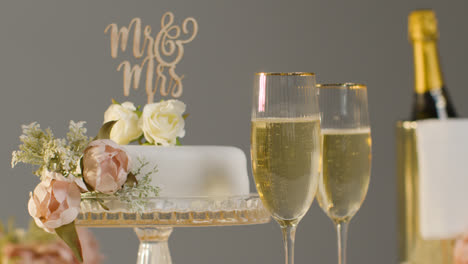 Wedding-Cake-With-Glasses-Of-Champagne-Against-Grey-Studio-Background-At-Wedding-Reception-1